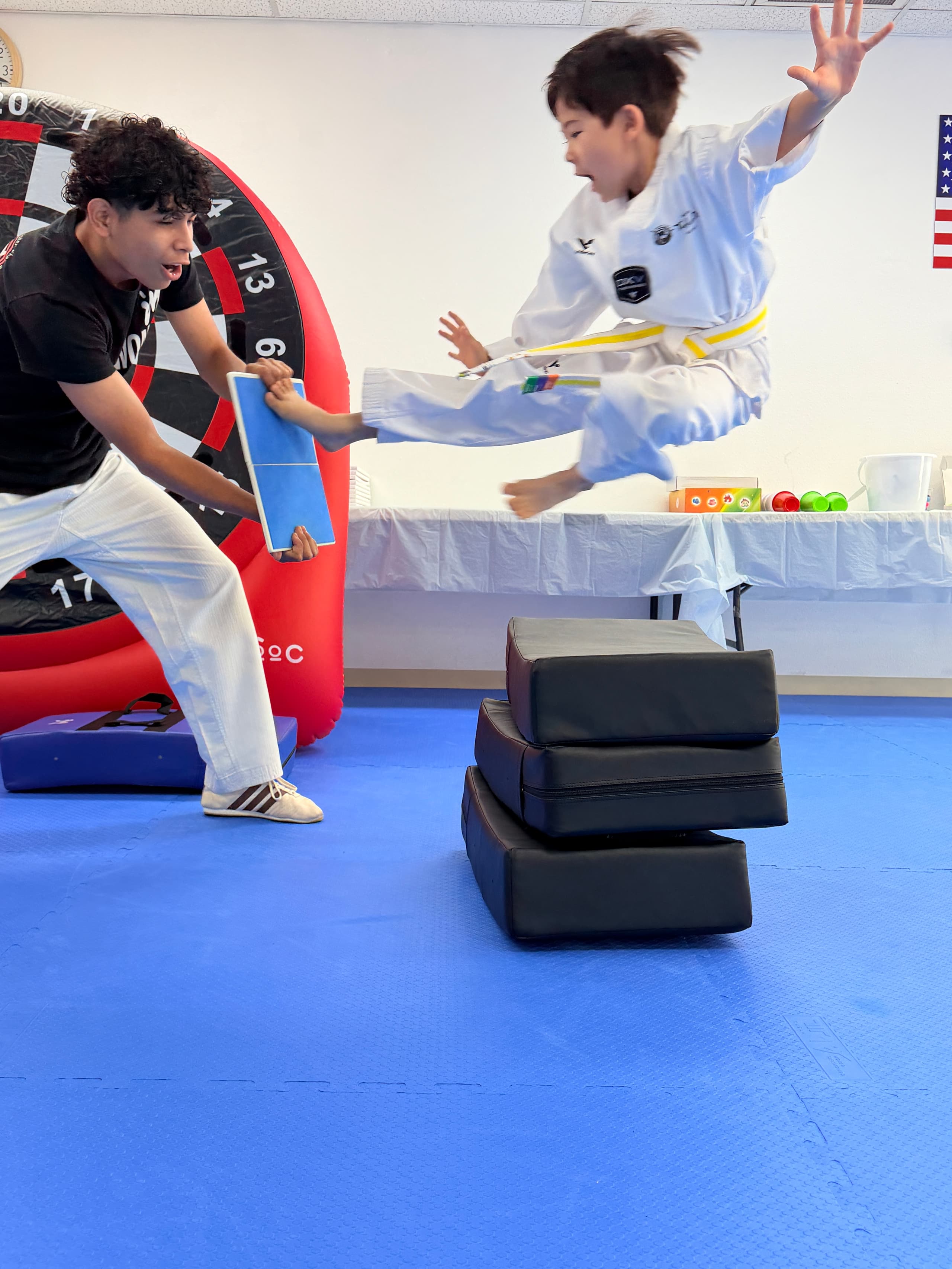 Yellow belt student breaking a board with a flying kick