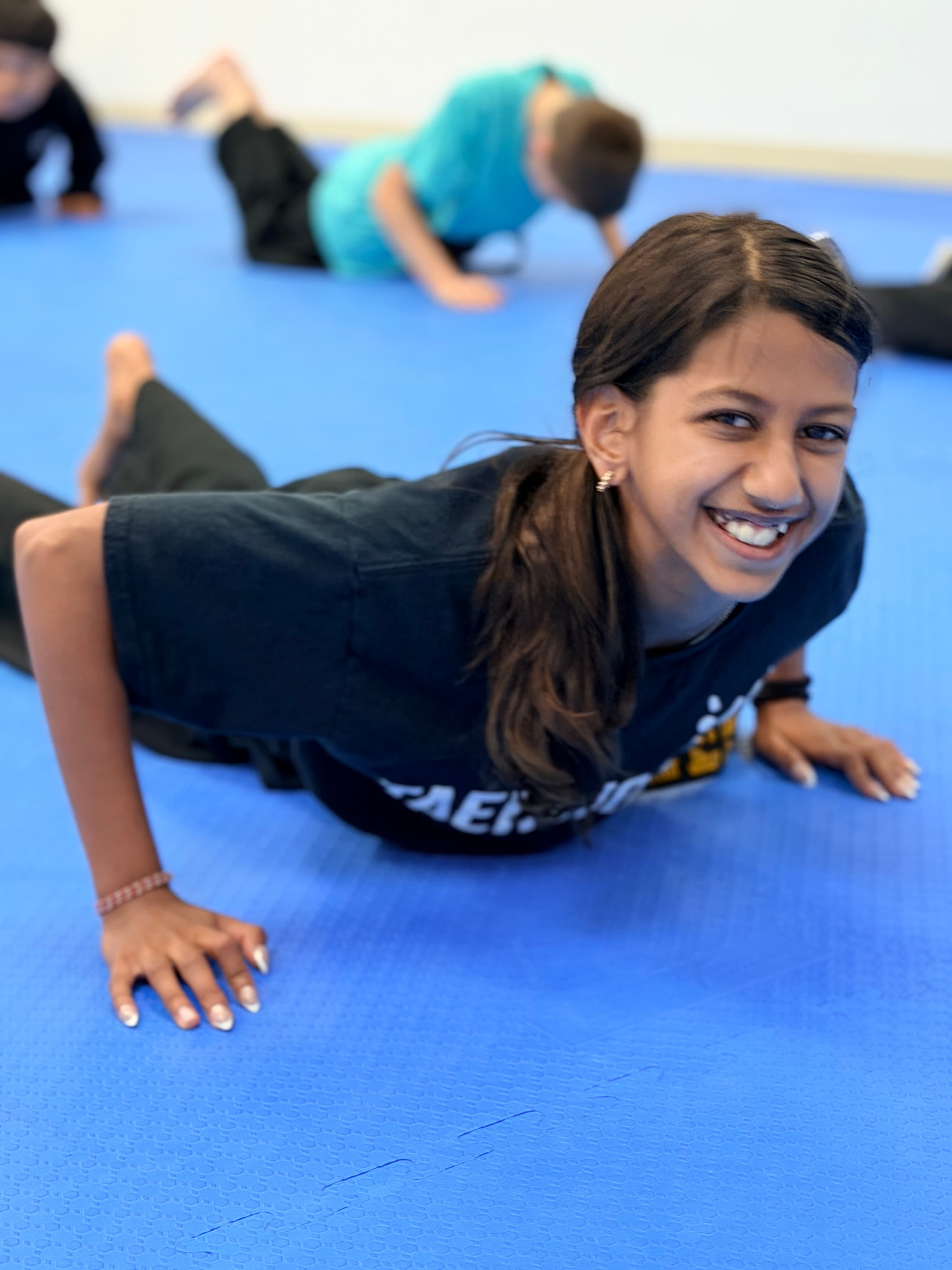 Smiling student doing push-ups on the blue mat