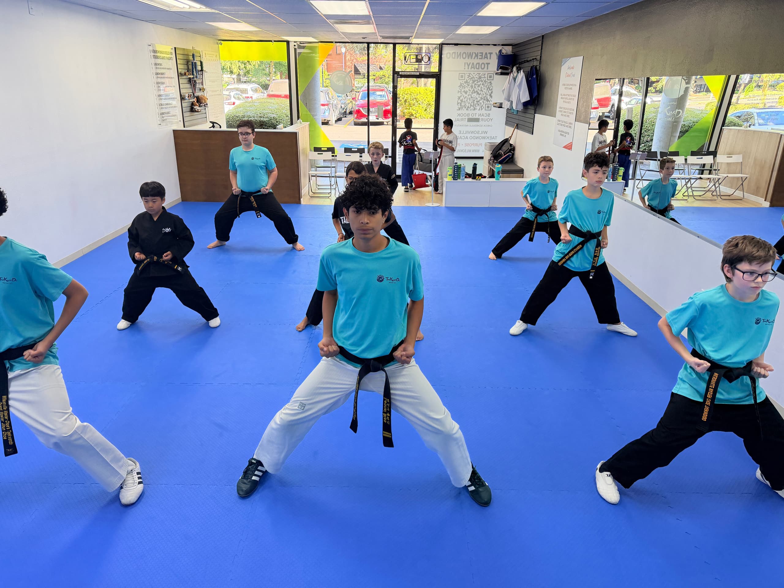 Black belt students holding a low stance together on the blue mat