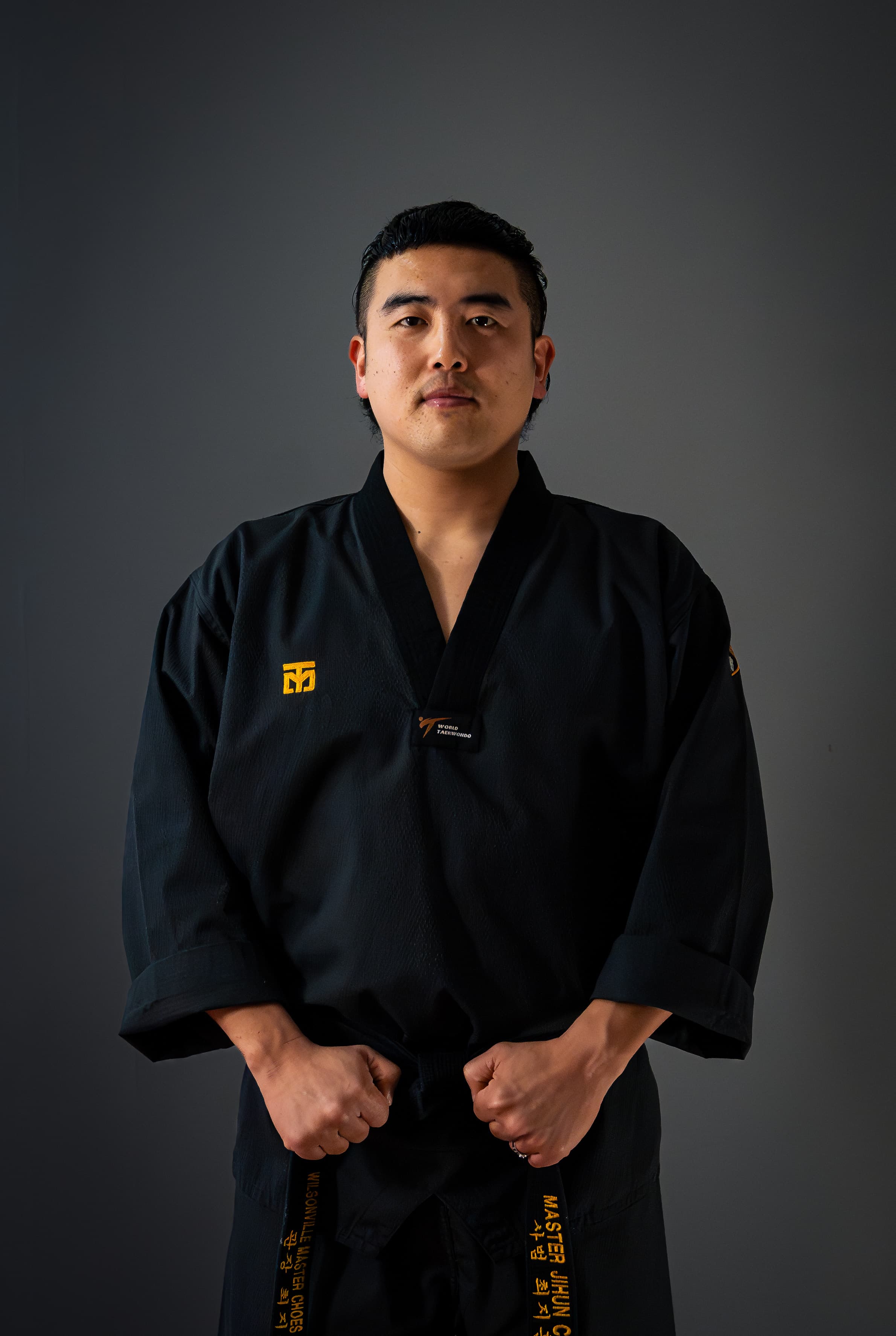 Master Choe standing in a black dobok holding his black belt