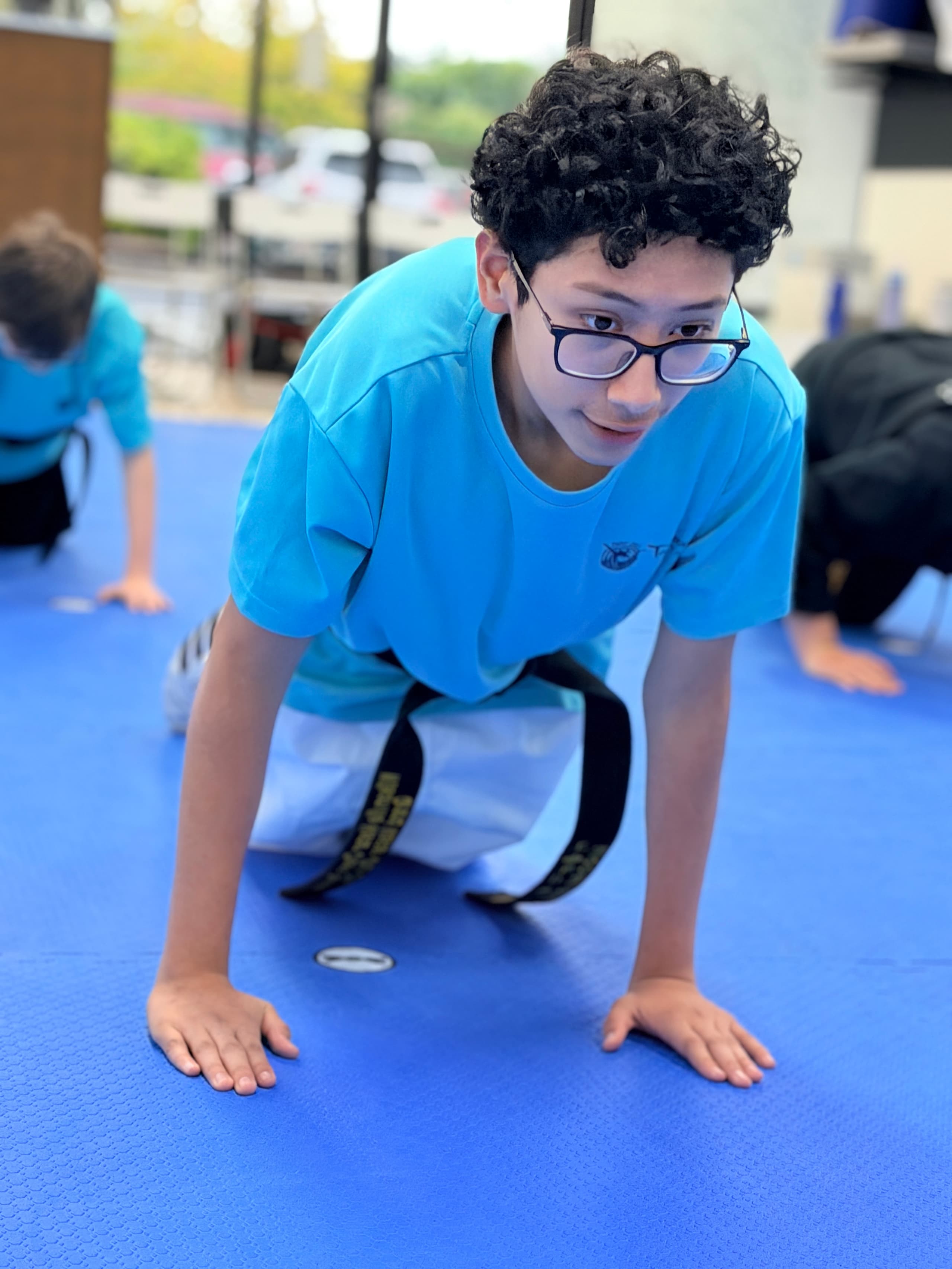 A student in glasses doing push-ups during warm-ups