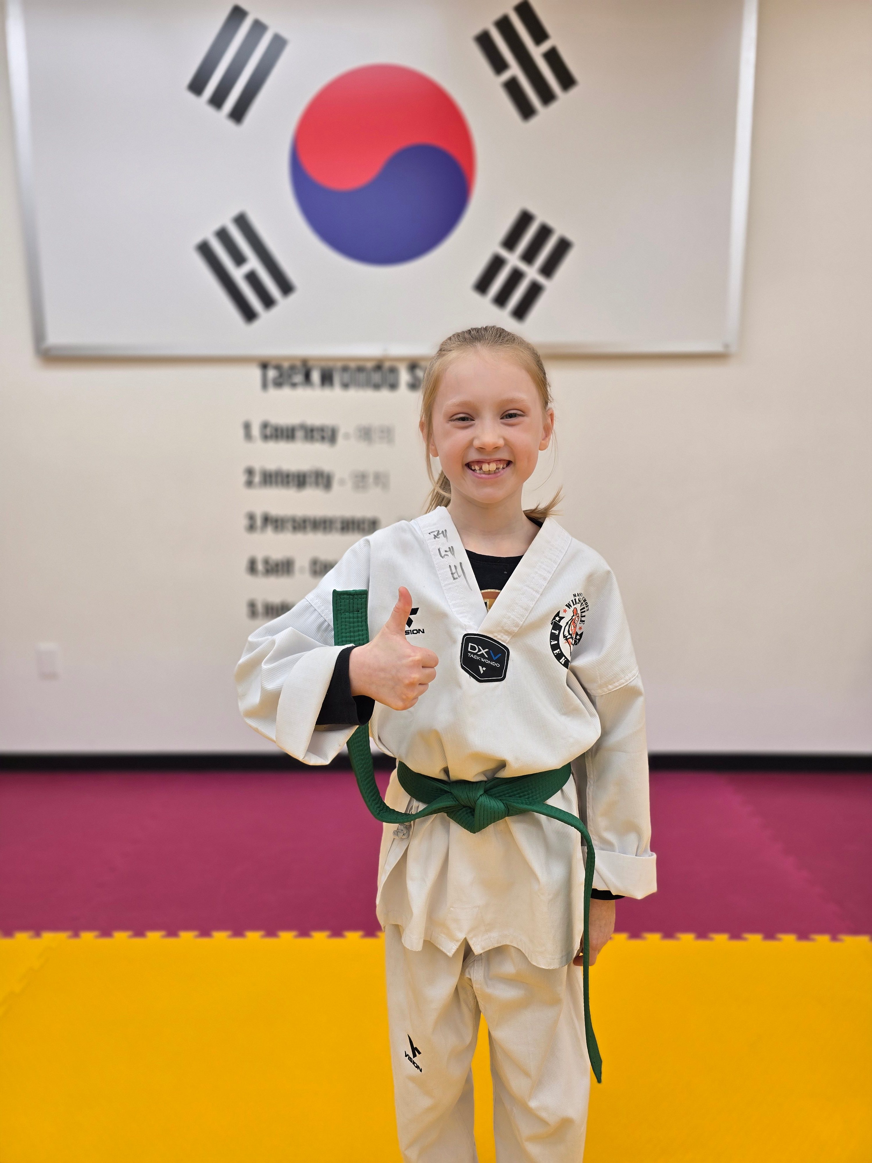 Smiling green belt student giving a thumbs up