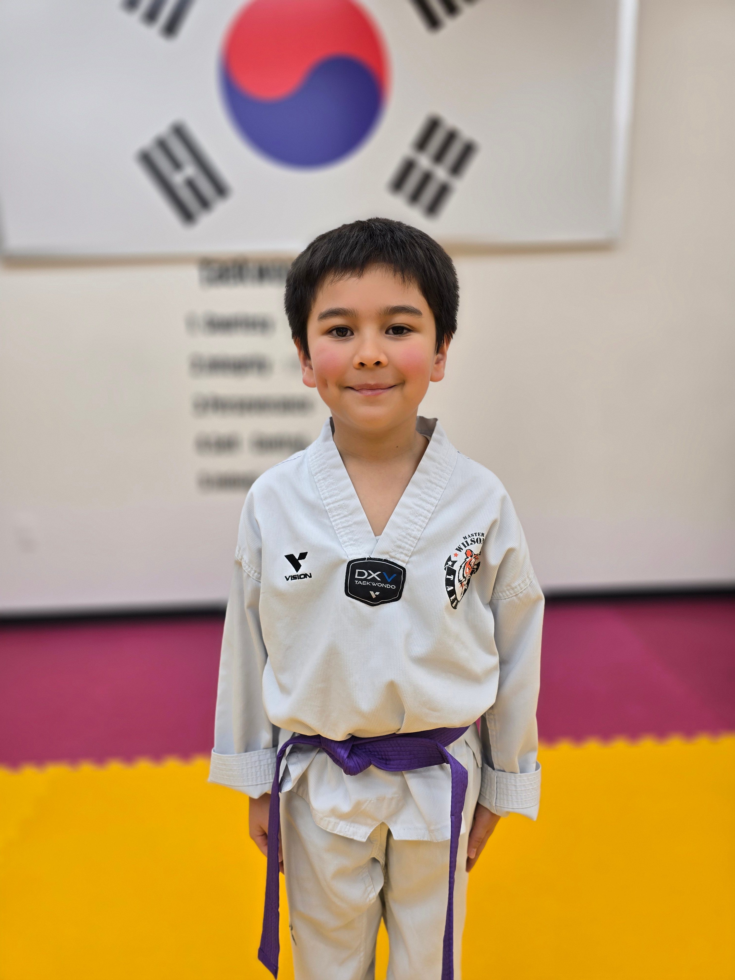 Young purple belt student in front of the Korean flag