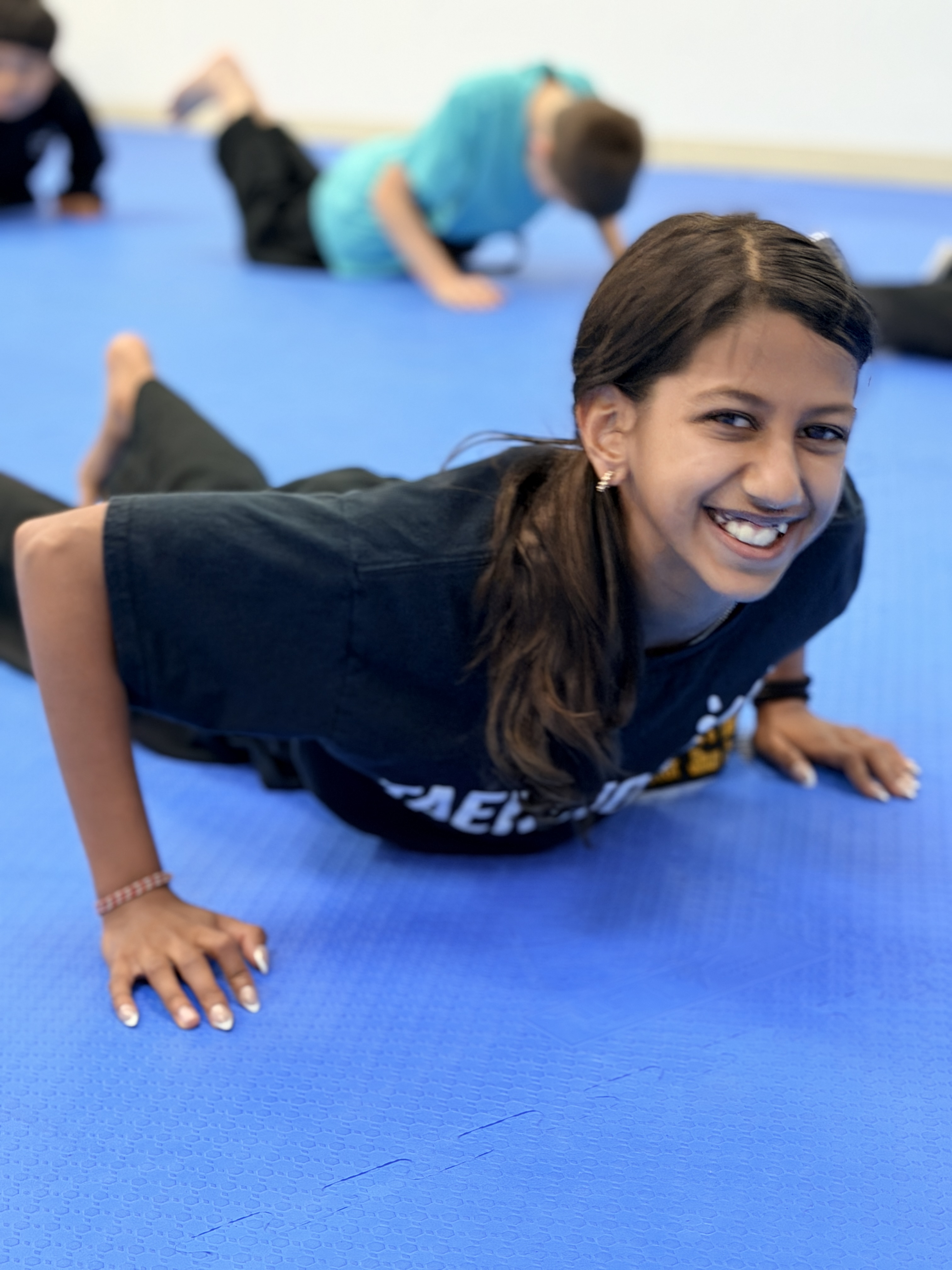 Smiling student doing push-ups on the blue mat