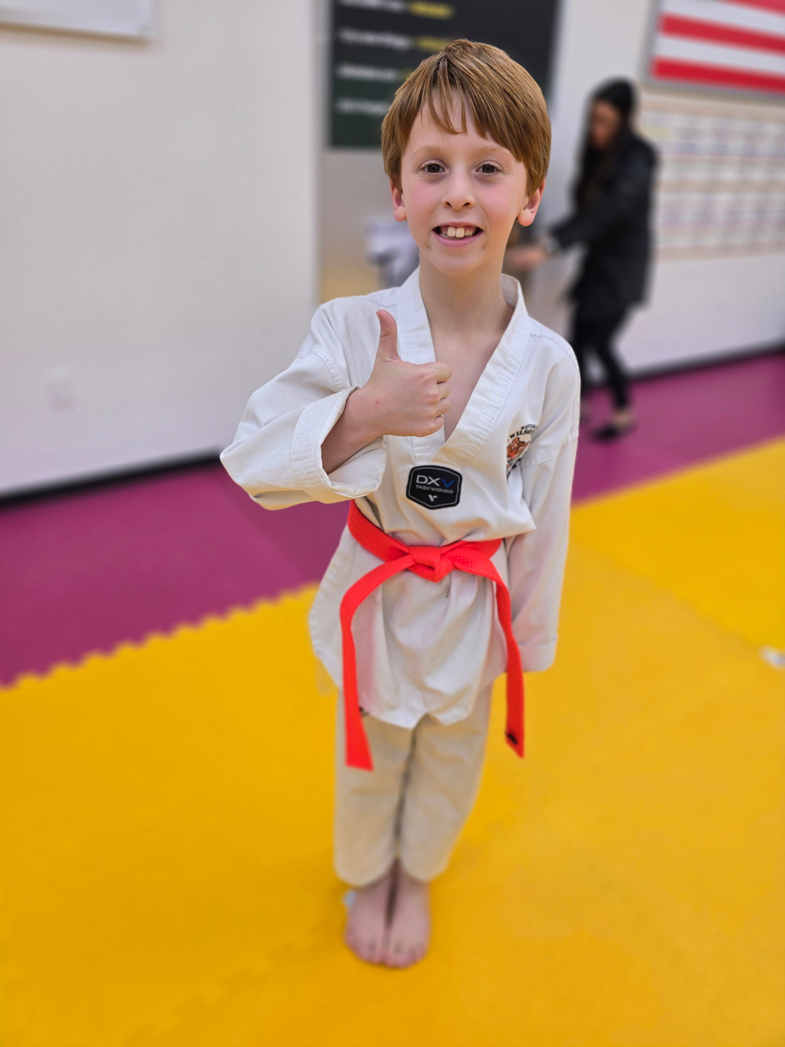 Red belt student giving a thumbs up on the mat