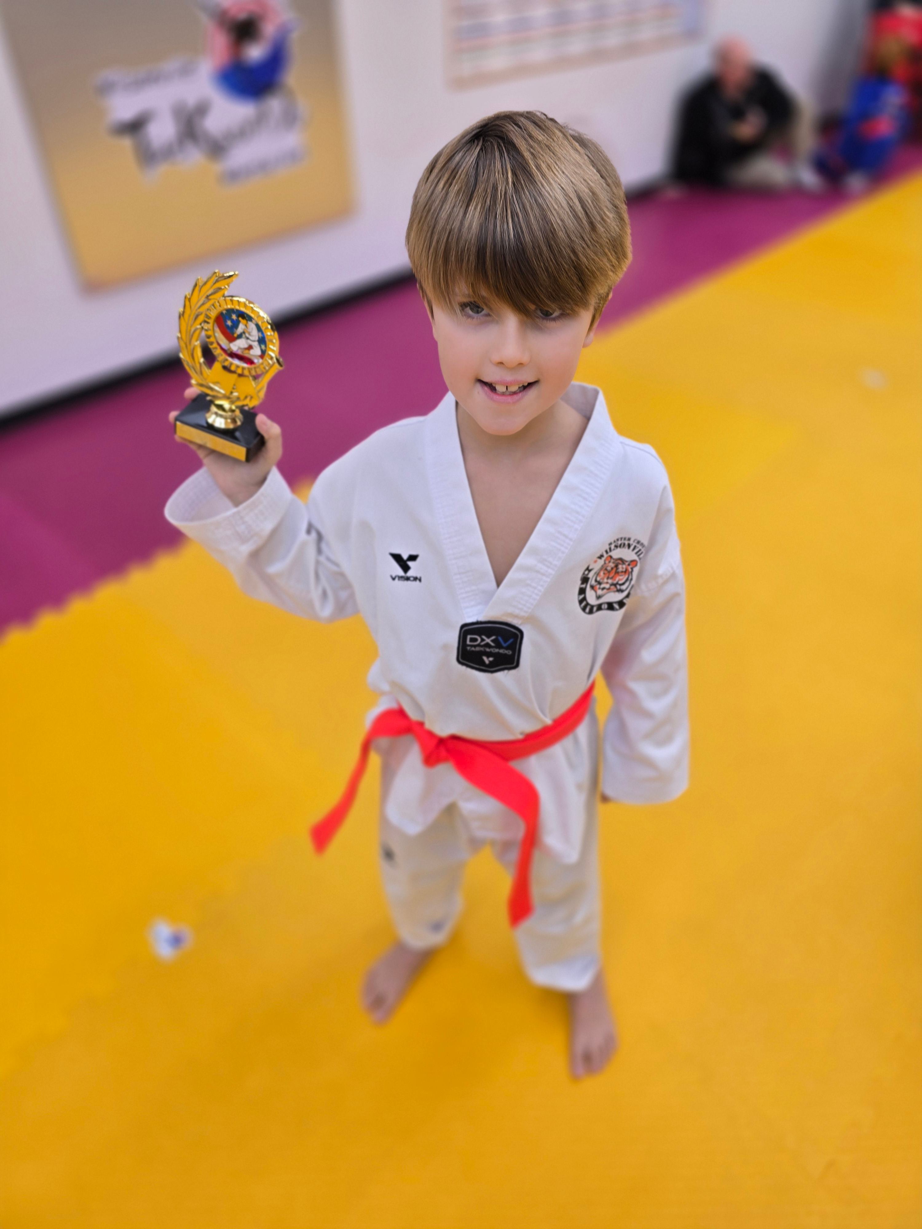 Red belt student raising his trophy