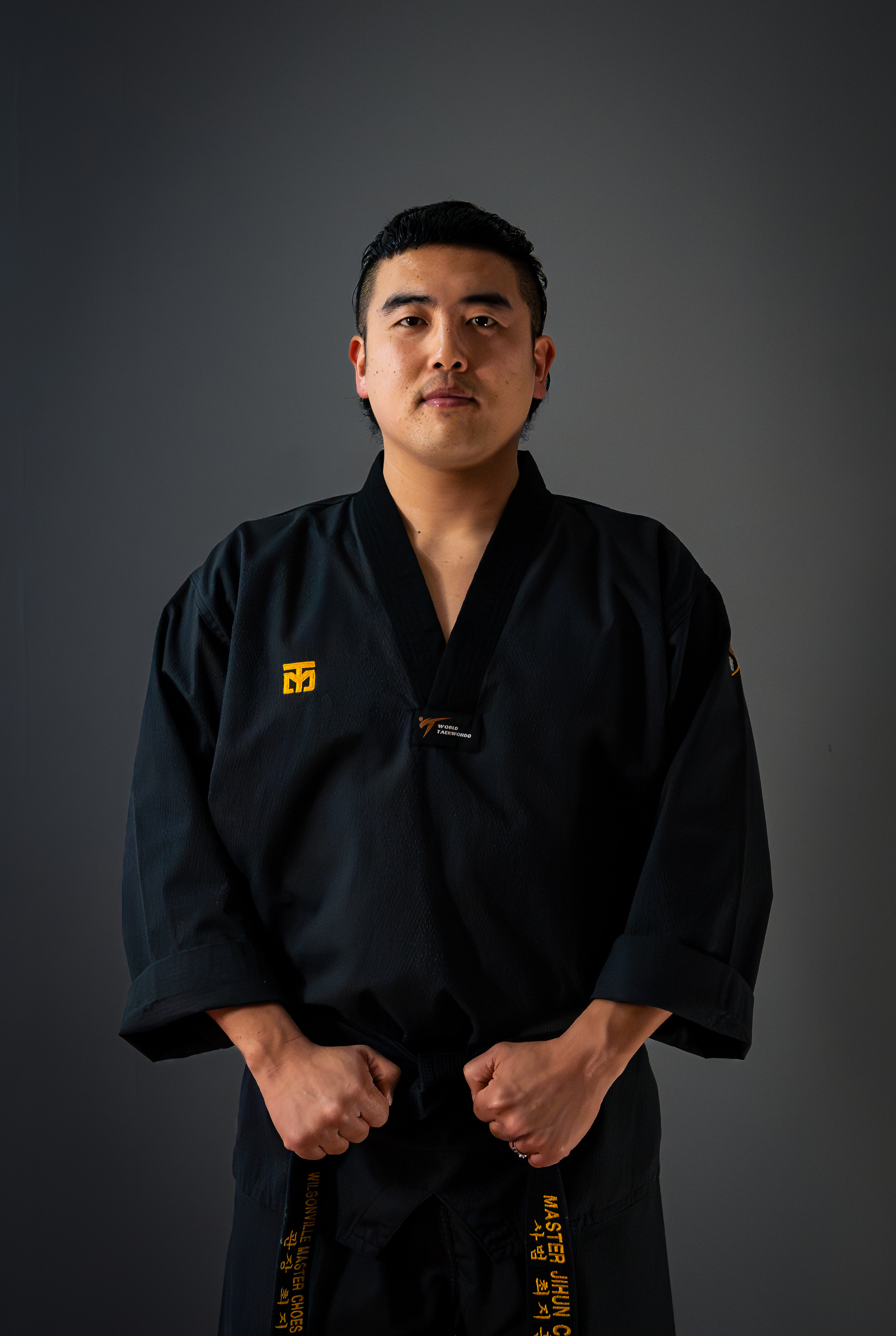 Master Choe standing in a black dobok holding his black belt